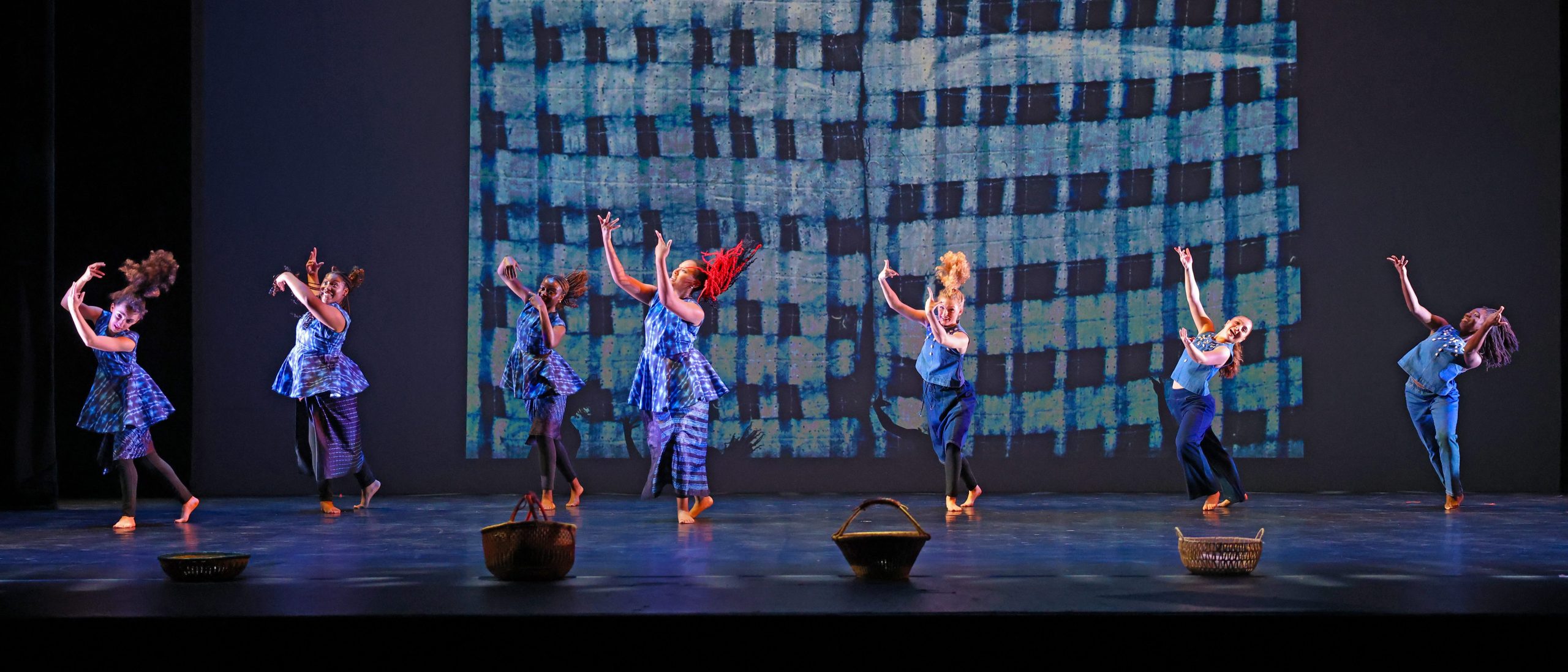 Dancers in an Afro-Brazilian piece performing on stage with colorful lighting and musician