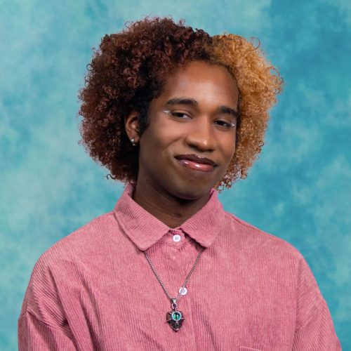 Ali Thiam in a pink shirt with a blue photo background