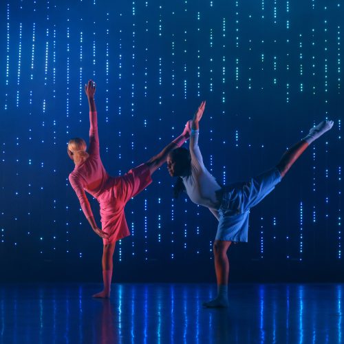 two dancers in front of dark blue LED screen