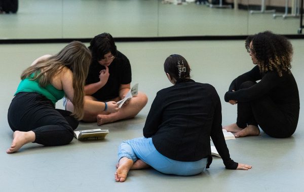 Four dance students sitting and reading in studio.