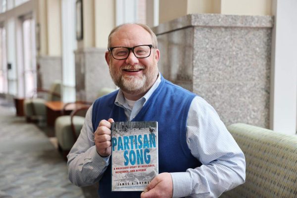 Jay Grymes holding his book, Partisan Song.