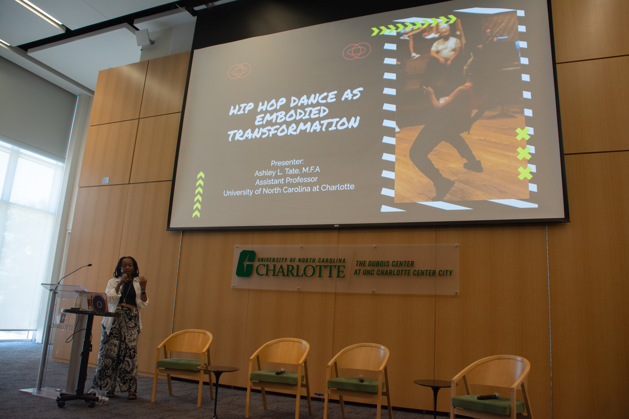 Ashley Tate standing at a podium and presenting research about Hip Hop as embodied transformation.
